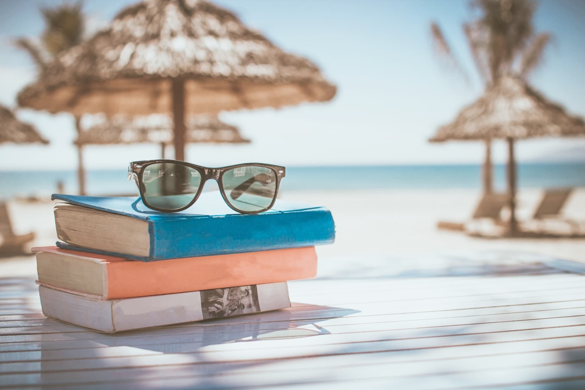 Beach scene with sunglasses and books representing the freedom of well-managed wealth
